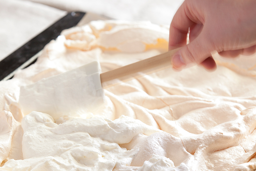 Met een spatel door de licht roze meringue